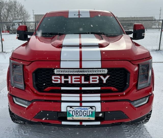 Red Ford F-150 with white racing stripes standing in the snow
